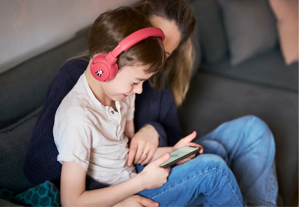 Kind mit Mutter und Hörbuch auf den Ohren
